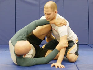 One person on their side on the ground with another person attempting to progress past their legs. Bottom player is blocking top player&rsquo;s progress using their top knee, arms, and hands.